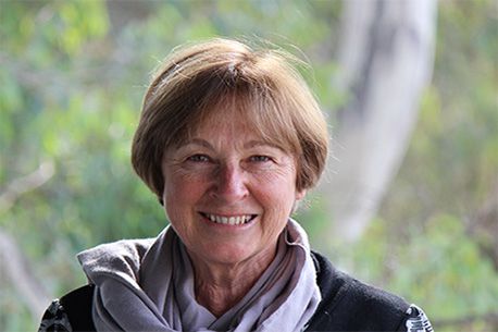 Portrait of Professor Valerie Braithwaite smiling at the camera wearing a grey scarf around her neck