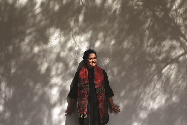 Sonali standing against a wall smiling 