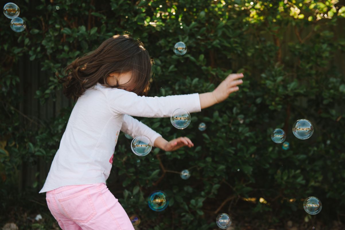A young girl playing in bubbles having fun