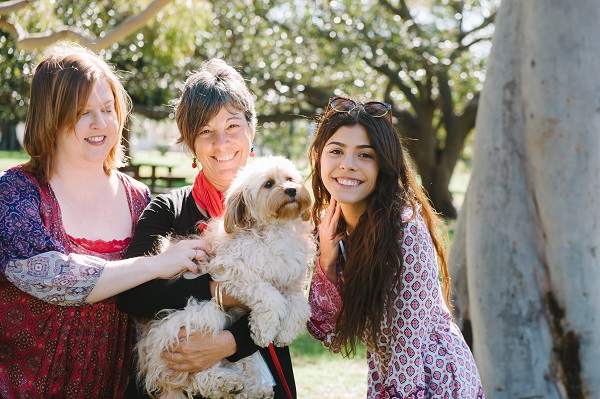 Three females holding a small dog all smiling
