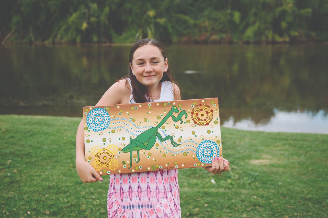 A picture of Chloe holding an Aboriginal painting