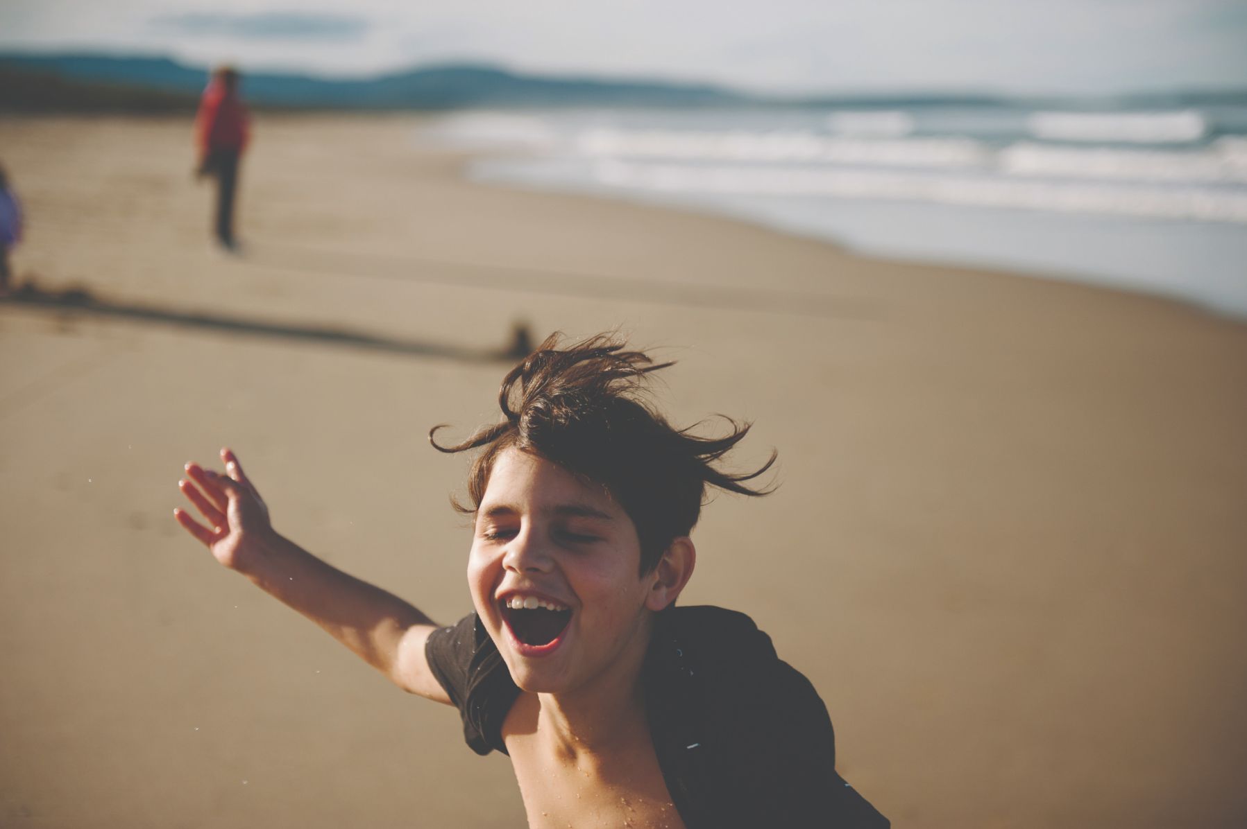 A young child running on a beach having fun