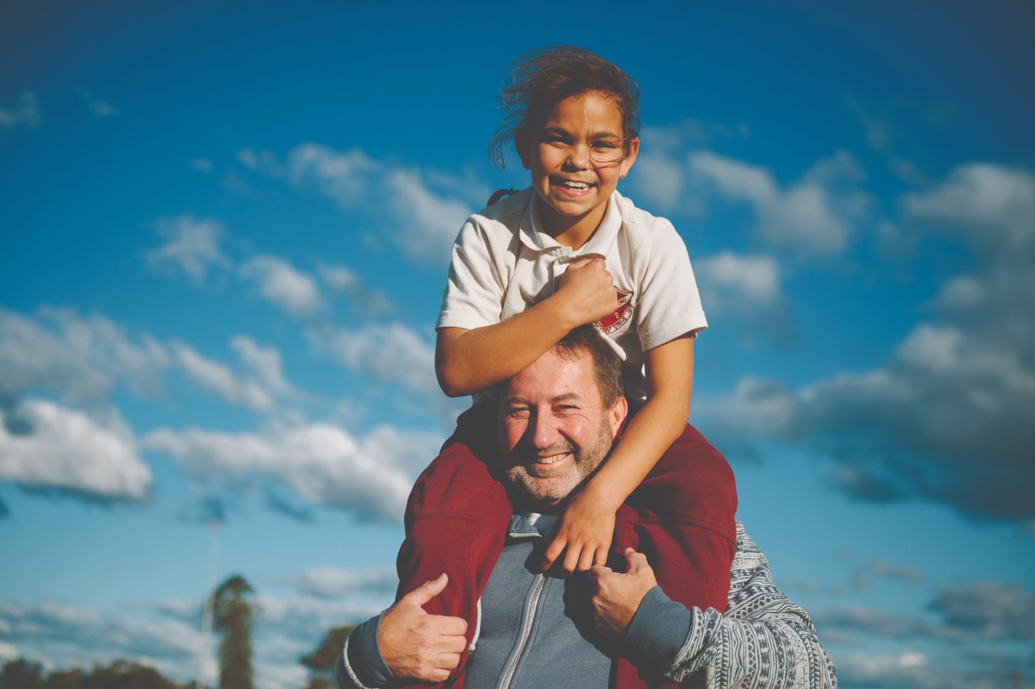 A young girl smiling and happy whilst on a mans shoulders