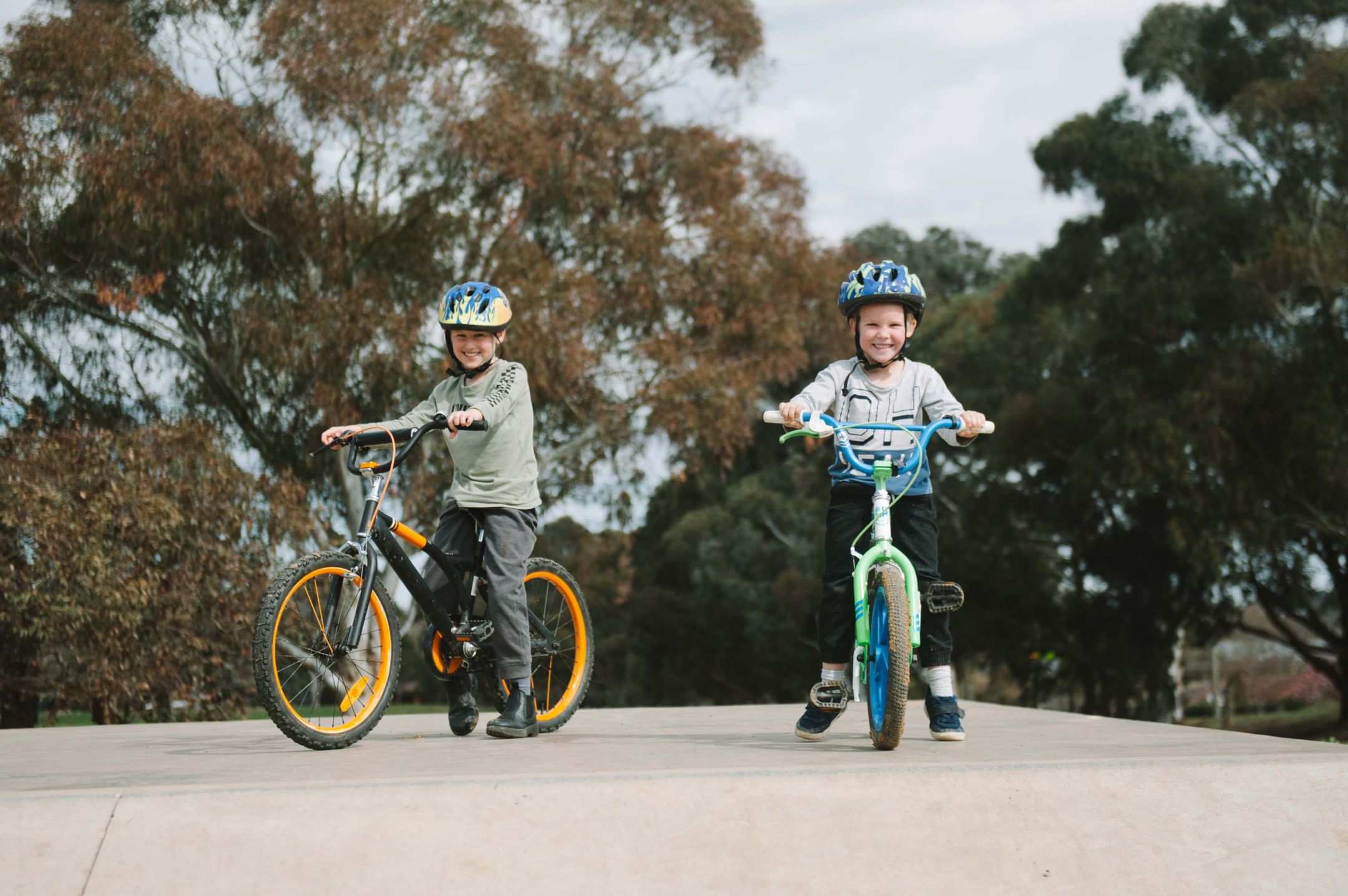 Two young boys wearing helmets and riding bicycles
