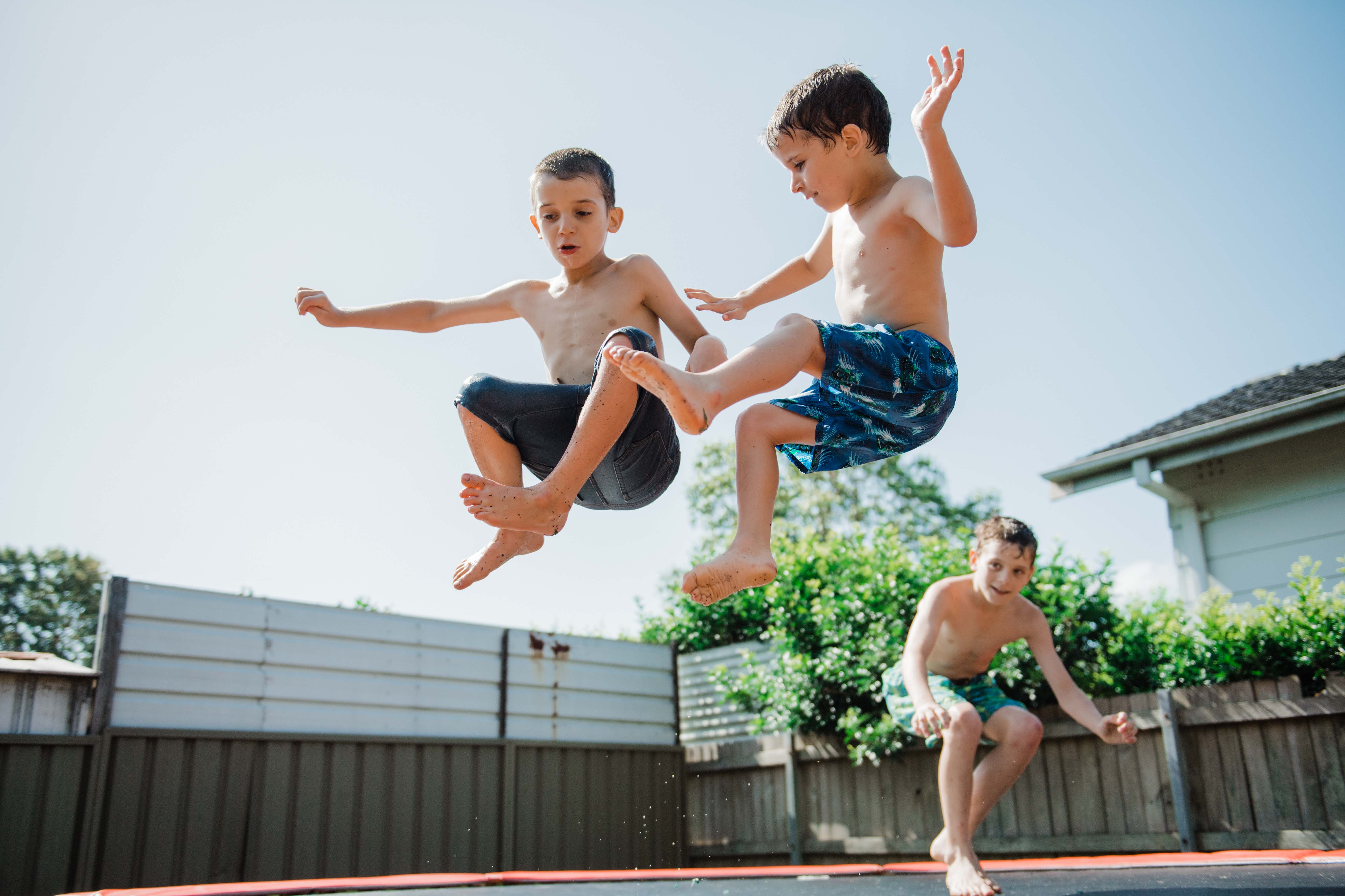 Two young boys jumping on a trampoline 