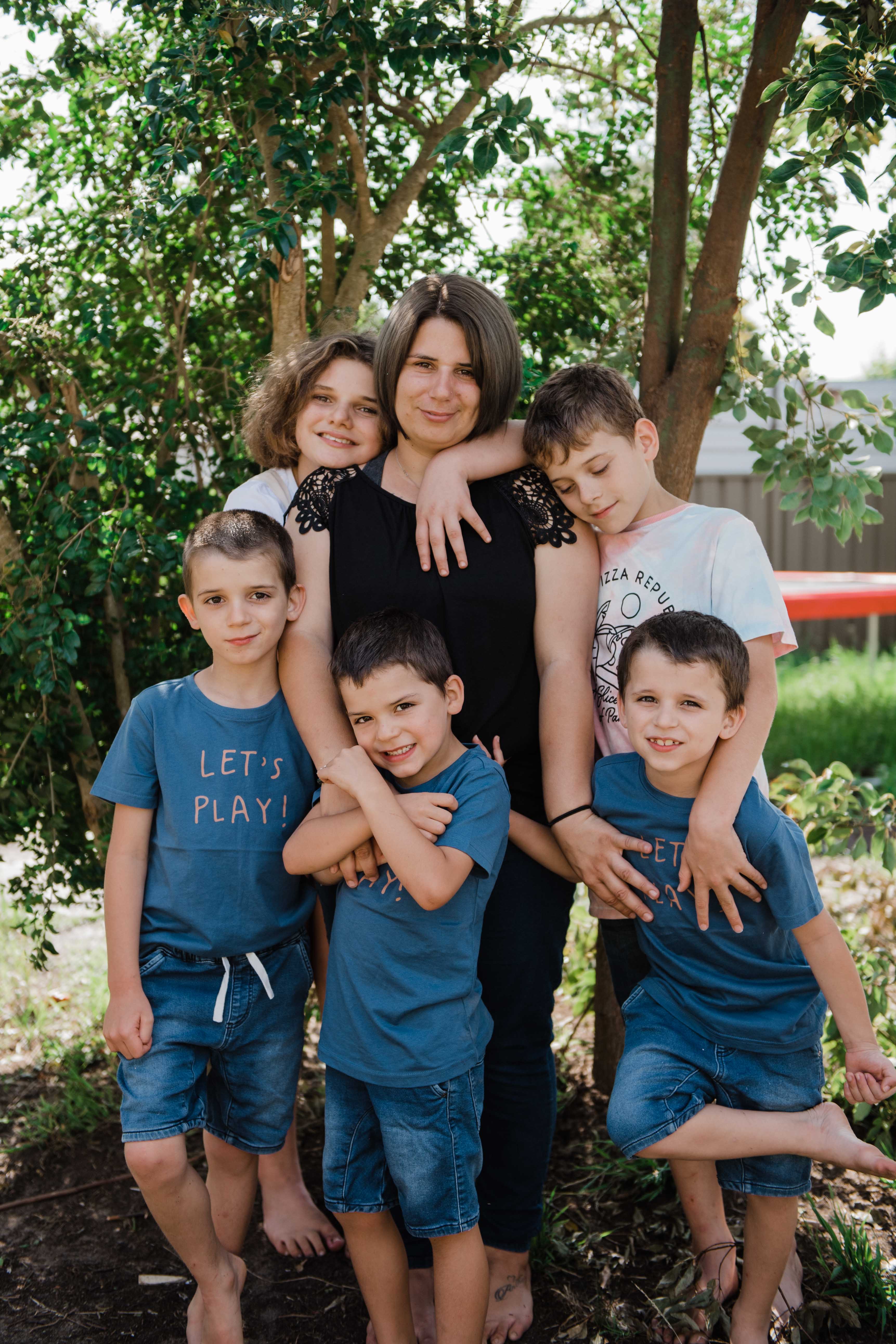 A picture of a female and five children hugging 