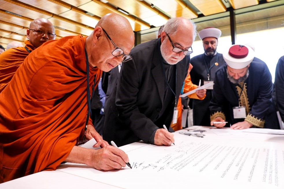 Religious leaders signing the unity declaration on a table 