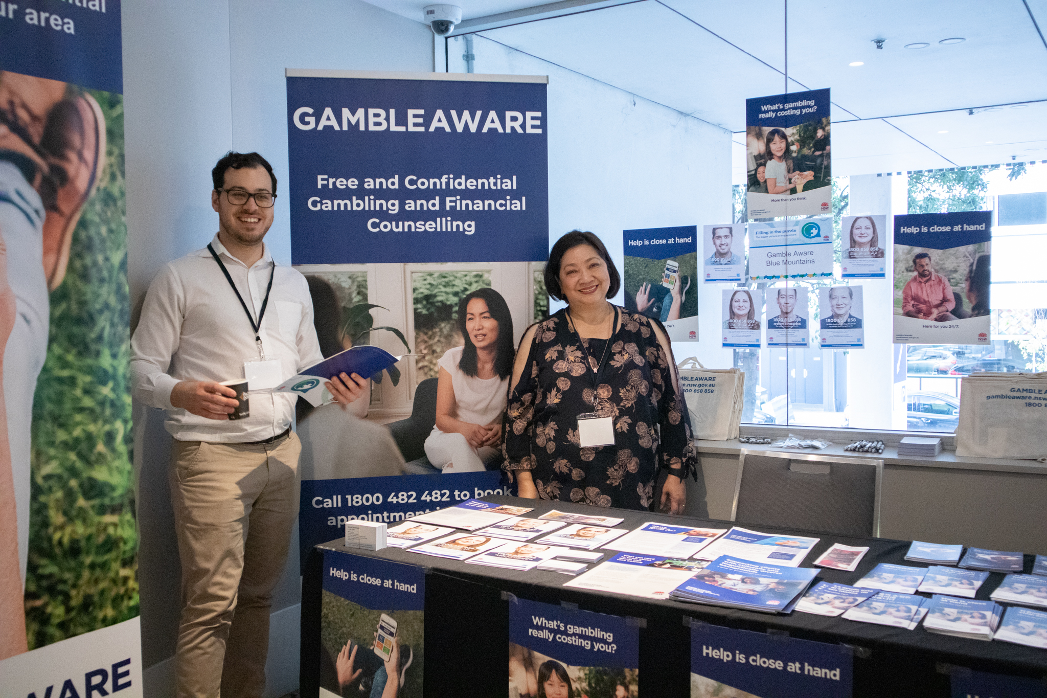 Two people standing at the Gamble Aware table, surrounded by pull-up banners, posters and brochures.