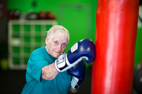 Margaret wearing boxing gloves, striking a punching bag.