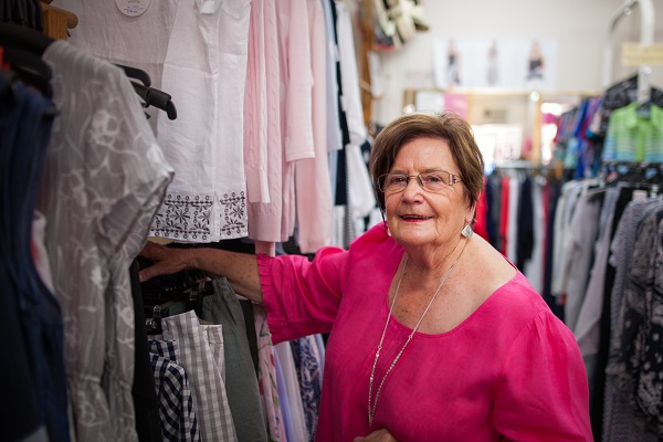 Carol standing next to dresses in her store