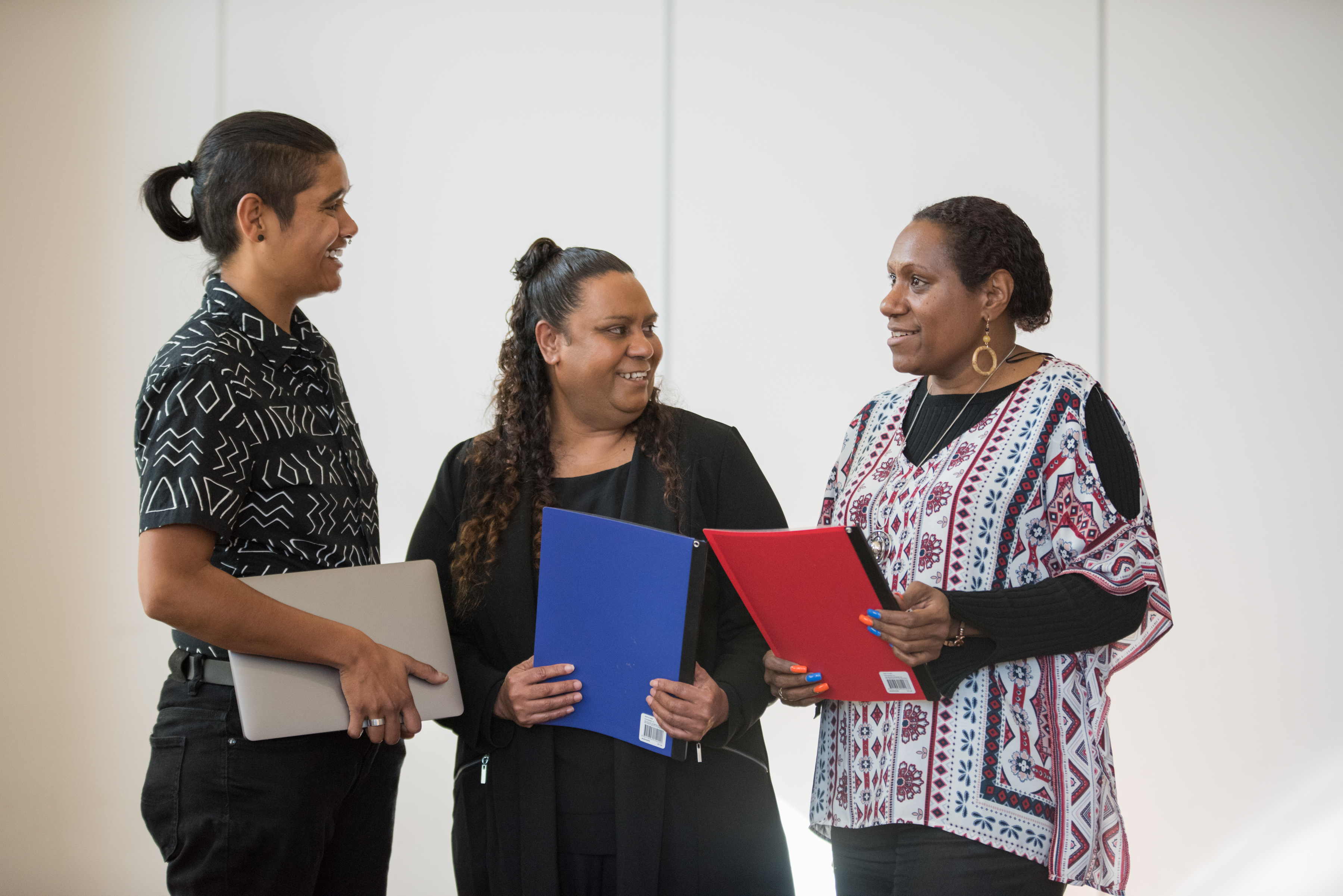 Three Aboriginal women holding folders